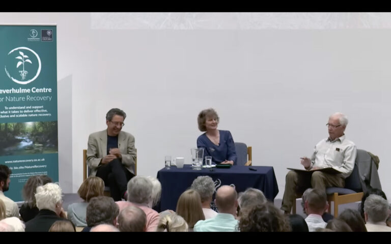 Allan Savory and George Monbiot debating on stage at Oxford